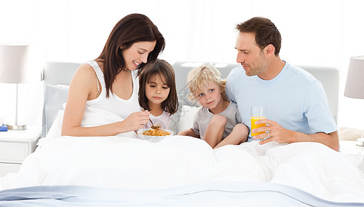 可爱的家庭在床上吃早饭图片