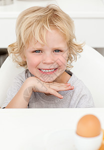 小可爱男孩坐在桌边吃煮鸡蛋的饭桌上图片