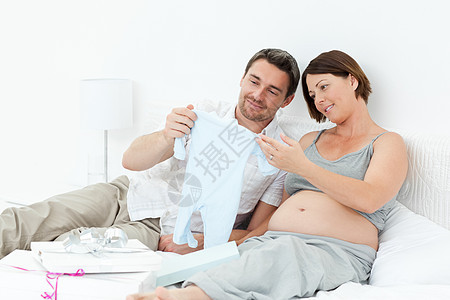 年轻未来的父母穿着乳衣怀孕女性父亲妻子微笑几个月母性母亲喜悦卧室图片