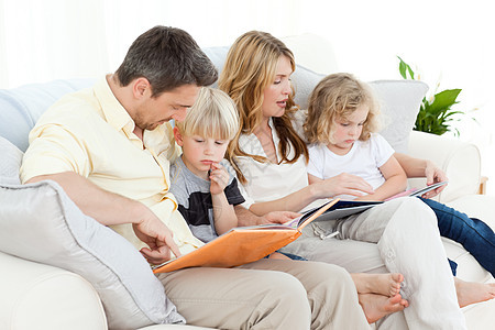 家人在沙发上读书后代父亲乐趣男人母亲父母喜悦女孩们阅读女性图片