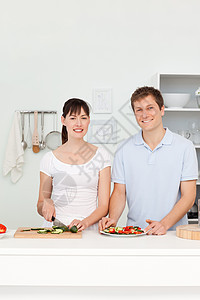 年轻一对看镜头的年轻夫妇洋葱午餐菜肴平底锅乐趣幸福女士烹饪勺子男人图片