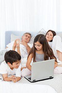 儿童在父母说话时看着他们的笔记本电脑爸爸女性父亲乐趣说谎感情卧室女儿妈妈男性图片