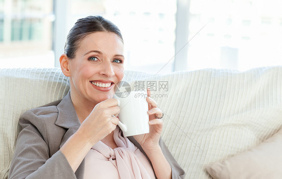 开心的女商务人士喝咖啡 喝咖啡黑发幸福长椅享受女士沙发女性饮料客厅房间图片