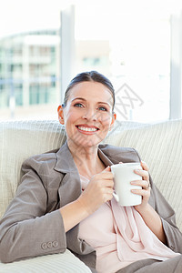 开心的女商务人士喝咖啡 喝咖啡饮料杯子女士幸福微笑黑发乐趣牛奶沙发咖啡图片