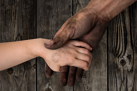 黑黑脏人的手握着孩子干净的手投标父母家庭童年帮助男人棕榈婴儿皮肤工人图片