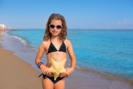有比基尼海星和太阳眼镜的蓝色海滩女孩眼镜幸福享受快乐太阳假期孩子海洋孩子们旅行图片