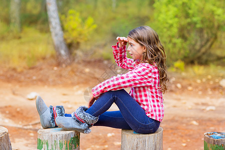 坐在森林后车厢的小女孩 在远处寻找树干前额季节休息女儿公园幸福乐趣童年孩子图片