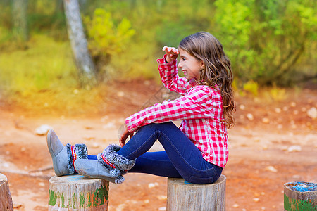 坐在森林后车厢的小女孩 在远处寻找微笑前额乐趣幸福探索松树季节女孩树干童年图片