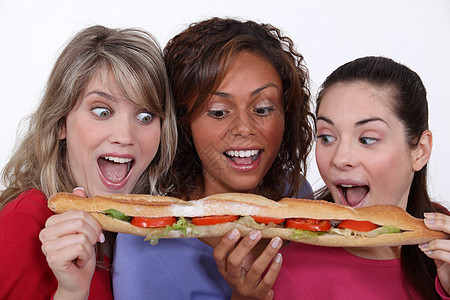 一群朋友吃一个长三明治的图片