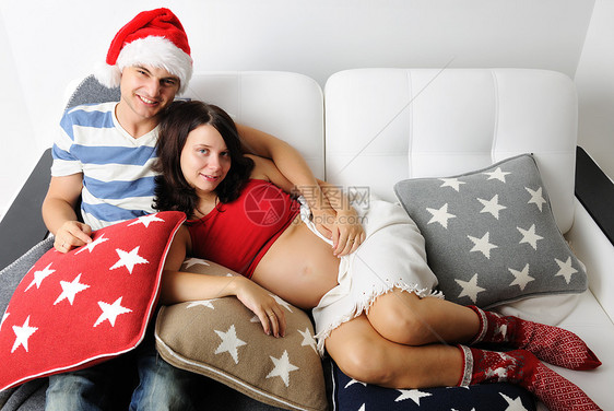 圣诞节时怀孕夫妇家庭成年人帽子沙发腹部婴儿幸福丈夫妻子喜悦图片