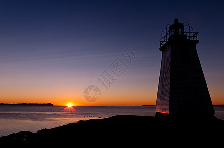 清晨日出时的灯塔天空日落海岸线支撑海岸太阳美丽太阳光红色黄色图片