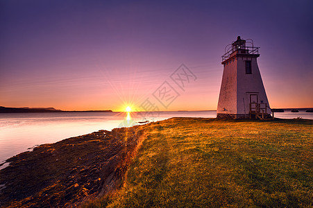 清晨日出时的灯塔红色海岸紫色太阳光地平线黄色支撑橙子海岸线射线图片