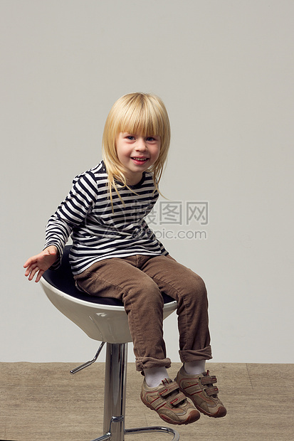穿着牛仔裤的3岁女孩坐在高椅子上金发宝贝发型身体孩子微笑凳子夹克高脚椅卷曲图片