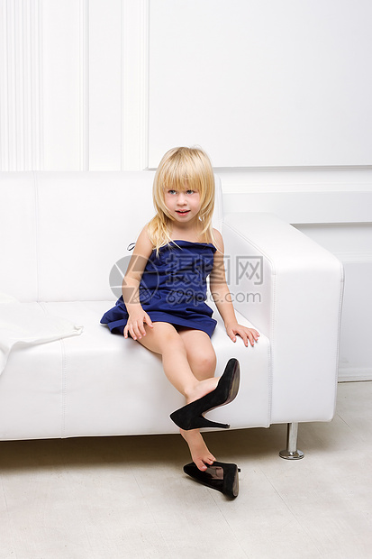 穿着高跟鞋坐在沙发上的小女孩蓝色女郎女性裙子妈妈鞋金发微笑幸福手提包工作室图片