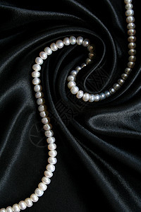 黑色丝绸上的白珍珠作为背景珠子细绳礼物奢华珠宝象牙光泽度宝石魅力宝藏图片