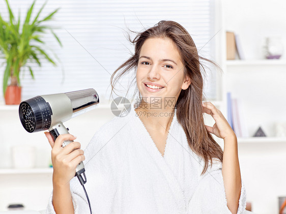 妇女在家里干头发植物女士家具房间棕榈浴衣白色发型图片