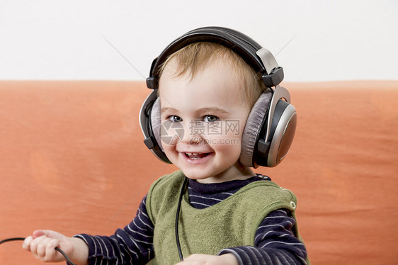 在沙发上带耳机的幼儿音乐手机电缆人脸绳索孩子水平婴儿人手儿童图片