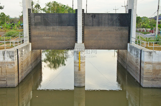 灌溉运河中的水和大坝大门齿轮溢洪道运输农作物生长天空水闸金属架子流动图片