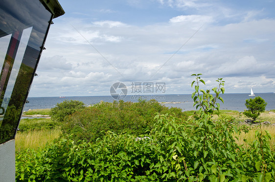 从灯塔查看天空场景生长晴天海岸海洋海岸线植被风暴帆船图片