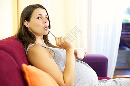 快乐的孕妇用酸奶舔勺子图片