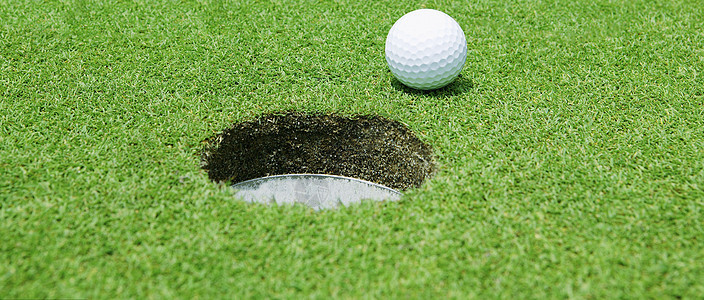 球在洞口附近的高尔夫球课程圆形娱乐推杆场地白色绿色游戏竞赛休闲图片