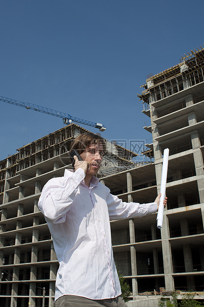 青年建筑师在建筑工地前通过电话发言图片