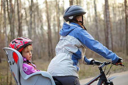 坐在自行车座椅上的孩子运动旅行女孩家庭座位头盔婴儿母亲童年闲暇图片