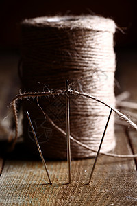 木头表面的细线和针工艺纺织品缝纫闲暇艺术工具工作桌子纤维宏观图片