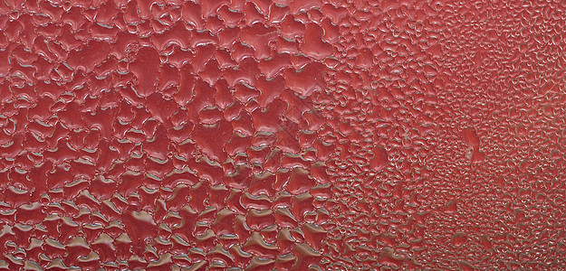 水滴在抽象的红色表面背景图片