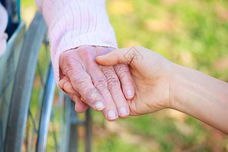高级和青年妇女握手女性绿色轮椅祖母皮肤公园家庭帮助手指老年图片