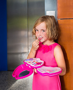在电梯门上打化妆口红的小女孩女婴图片