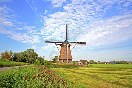 荷兰乡村的传统风车行人蓝色烟囱旅游建筑学天空房子运河桑色村庄图片