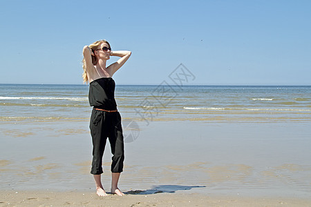美丽的女人在沙滩上放松头发游泳衣幸福天空海滩享受泳装太阳女孩比基尼图片