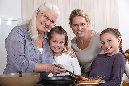 母亲 祖母和女孩做煎饼图片