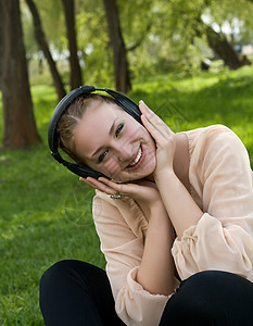坐在草地上听户外音乐和歌舞的快乐女人图片