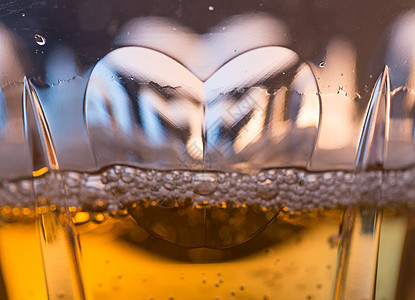 香槟杯中心脏的宏观近距离拍摄茶点长笛饮料黑色白酒溪流黄色液体奢华背景图片