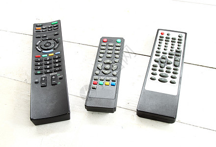 白桌上的三台远程控制塑料木头渠道数字电视钥匙键盘技术视频工作室图片