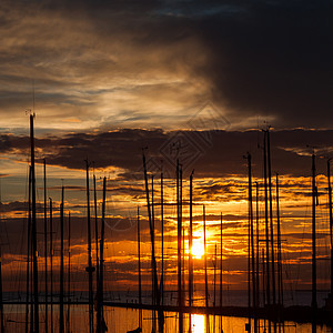 以日落时的游艇为港湾橙子桅杆运输娱乐光束太阳旅行钓鱼蓝色帆船图片