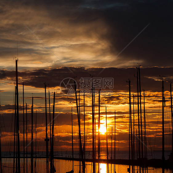 以日落时的游艇为港湾橙子桅杆运输娱乐光束太阳旅行钓鱼蓝色帆船图片