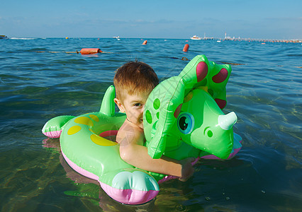 在海浪中的小男孩假期喜悦乐趣晴天童年孩子季节海滩蓝色海洋图片