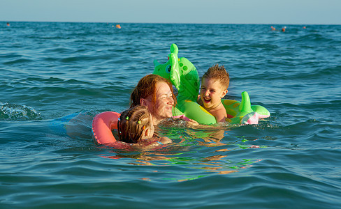 在波浪中的家庭晴天海洋海浪女孩乐趣童年假期孩子蓝色季节图片