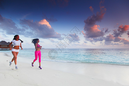 两个女人在沙滩上奔跑赛跑者运动装天空成人运动员日落运动海洋慢跑者跑步图片