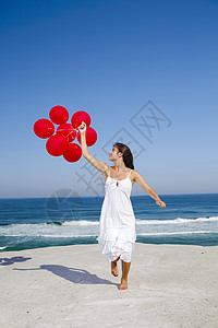 美丽的女孩带着红色芭蕾舞女郎跑来跑去飞行蓝色自由天空气球闲暇晴天幸福享受乐趣图片