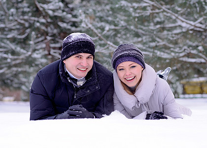 年轻微笑的情侣在雪上撒谎的肖像女士女孩成人男人男性家庭拉伸女性快乐幸福图片