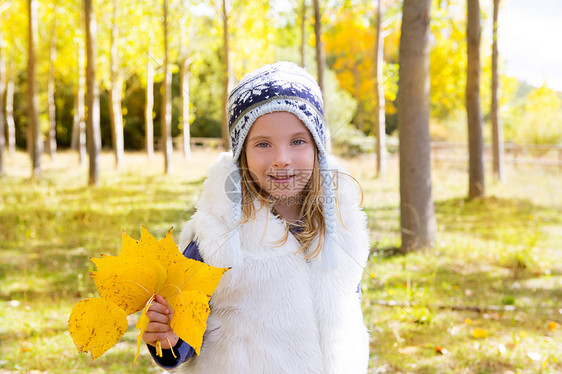 秋天的童女儿童 在阴花林中 黄色落叶手握着森林孩子们女性树干微笑树叶童年金发蓝色帽子图片