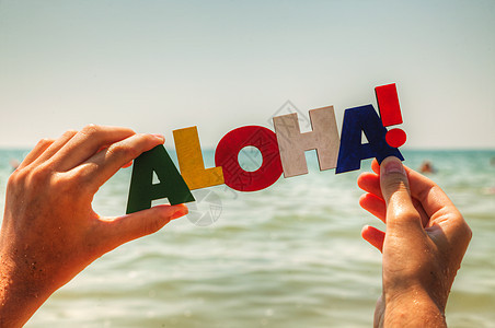 女性手握着色彩多彩的Aloha字字母海滩文化假期阳光游客热带问候语旅行图片