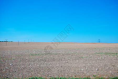 草地和电线对着蓝天太阳场景天空土地场地蓝色全景天气车道牧场图片