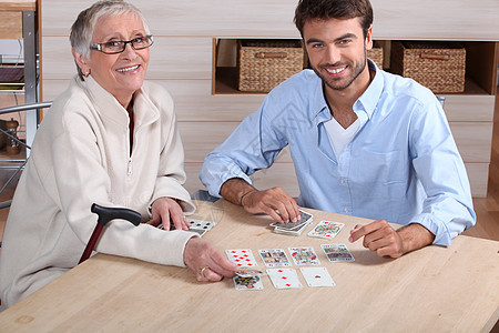 与年长妇女一起打牌的年轻人背景图片