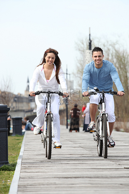 年轻夫妇沿木板行道骑自行车图片