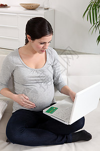 使用笔记本电脑的孕妇卡片腹部女性夫妻生命力长椅肚子互联网微笑父母图片